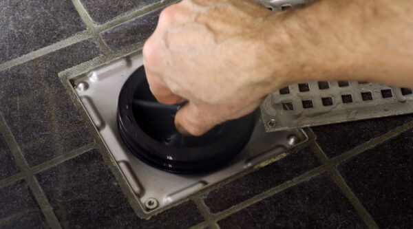 Zdjecie-przedstawiajace-dlon-umieszczajaca-syfon-suchy-green-drain-w-odplywie. Zdjecie-przedstawiajace-dlon-umieszczajaca-syfon-suchy-green-drain-w-odplywie.